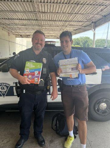 Port Clinton school resource Officer Curt Cochran, left, welcomes Daniel Bookman Nemerzitski — a university student from Estonia who is participating in a summer exchange program — who recently received a solicitation permit. He will introduce families with school-aged children to educational books and learning apps.
